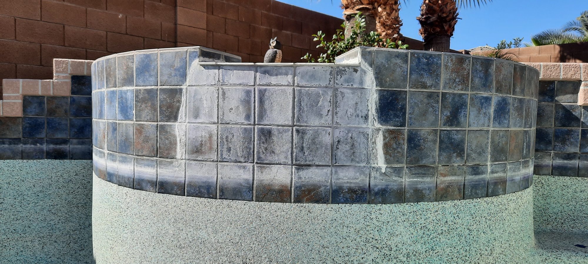 Dark blue pool water line before dustless blasting